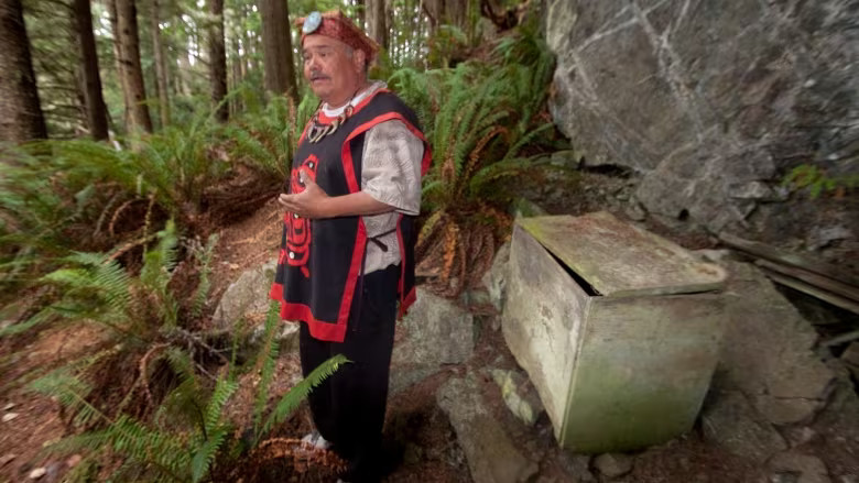 Aboriginal tourism operator Tom Sewid stands near a First Nations burial box on a remote Island in British Columbia's Broughton Archipelago in an undated handout photo. Sewid's actions, giving travellers full access to ancient burial boxes, including revealing the skeletal remains, have been condemned by his fellow First Nations. (Katy Palladina/Canadian Press)